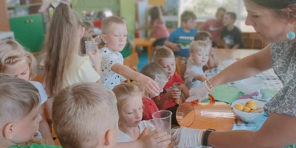 Pani wlewa wodę smakową do kubeczków dzieci.jpg