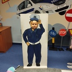 Chłopiec pozuje do zdjęcia za planszą z otworem na głowę i sylwetką policjanta .jpg