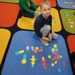 Chłopiec z figurami geometrycznymi na dywanie.jpg