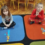 Dzieci z figurami geometrycznymi na dywanie.jpg