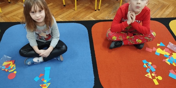 Dzieci z figurami geometrycznymi na dywanie.jpg