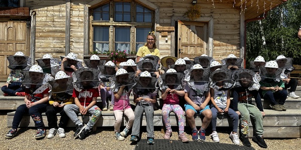 dzieci w kapeluszach pszczelarskich siedzą na schodach.jpeg