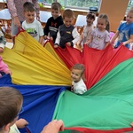 dzieci zawijają dziewczynkę w chustę