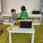 Chłopiec podaje koledze z zawiązanymi oczami owoc