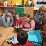 Dzieci z rodzicami podczas pracy przy stolikach.