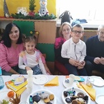 Dzieci z rodziną siedzą przy stole.