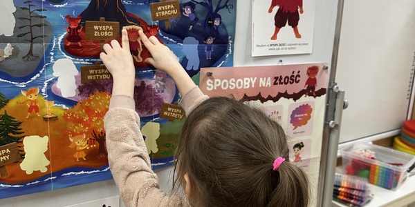 dziewynka przykleja Gniewka na plakacie projektowym.