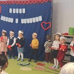 Dzieci śpiewają piosenkę trzymając serduszka