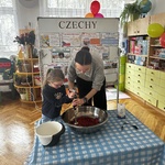 dziewczynka i pani blendują truskawki.