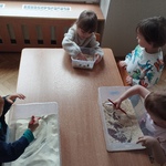 Dzieci odkrywają szkielety dinozaurów ukryte pod kaszą.