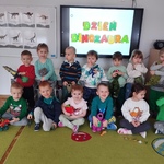 Dzieci z zabawkowymi dinozaurami pozują do zdjęcia.