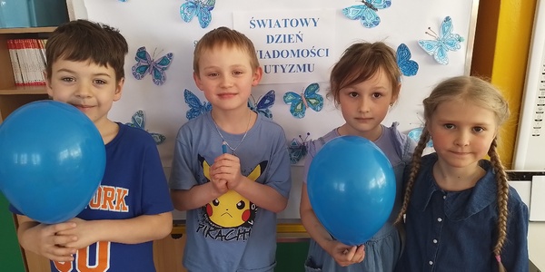 Dzieci ubrane na niebiesko trzymają balony.