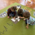 Dzieci układają na dywanie puzzle.