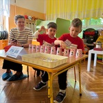 chłopcy manipulują kubeczkami.