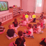 Dzieci oglądają bajkę i jedzą popcorn.