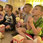 dzieci jedzą popcorn.