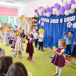 Dzieci tańczą z papierowymi kwiatkami 