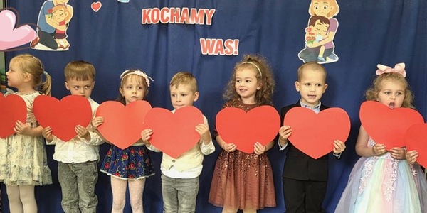Dzieci stoją razem i trzymają serduszka.