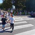 dzieci przechodzą przez jezdnię po pasach.