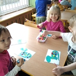 Natalka, Marysia i Piotruś układają pomponiki za pomocą szczypiec 