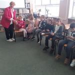 Pani bibliotekarka rozdaje pamiątkowe zakładki do książek.jpg